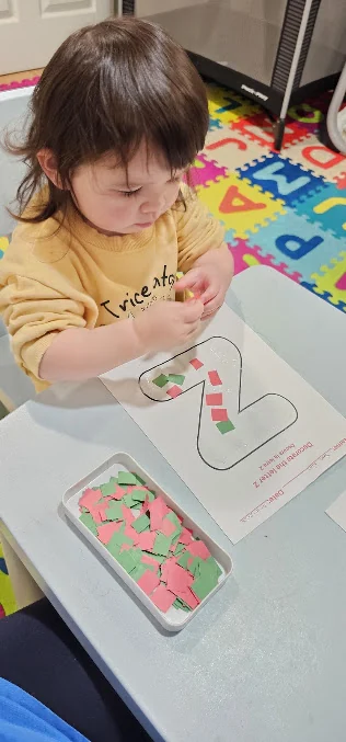 A child creating a colorful paper collage inside Happy Geniuses
