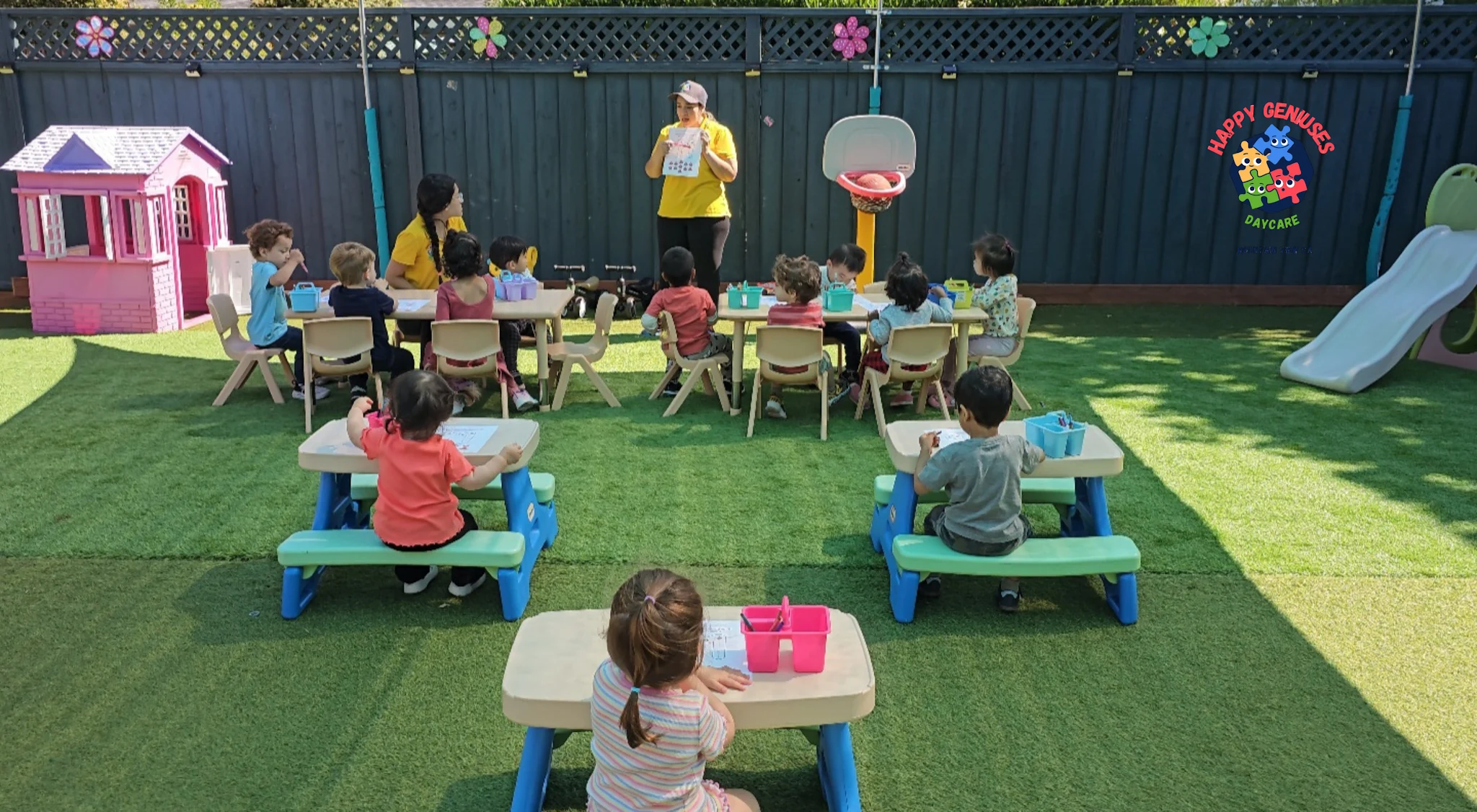 Children and caregivers taking part in an outdoor learning activity in the Happy Geniuses patio